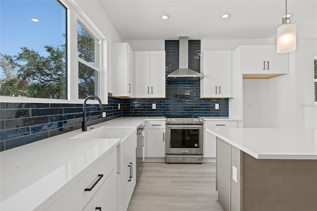 307 15th St N, Saint Petersburg, FL 33705 - kitchen featuring wall chimney exhaust hood, stainless steel electric range oven, light countertops, white cabinetry, and backsplash