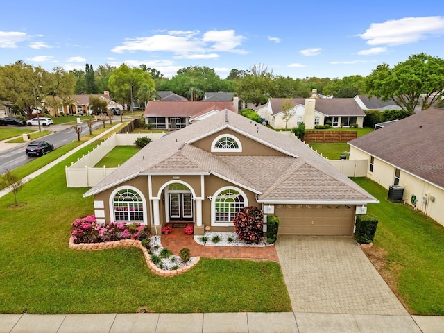 view of front of property featuring stucco siding, decorative driveway, a fenced backyard, roof with shingles, and an attached garage