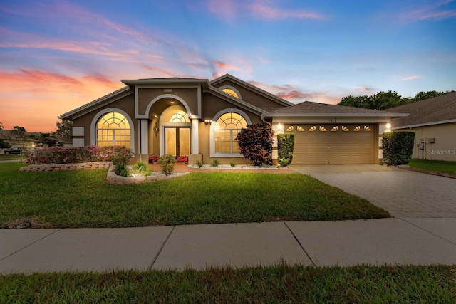 view of front of property with a front lawn, decorative driveway, an attached garage, and stucco siding