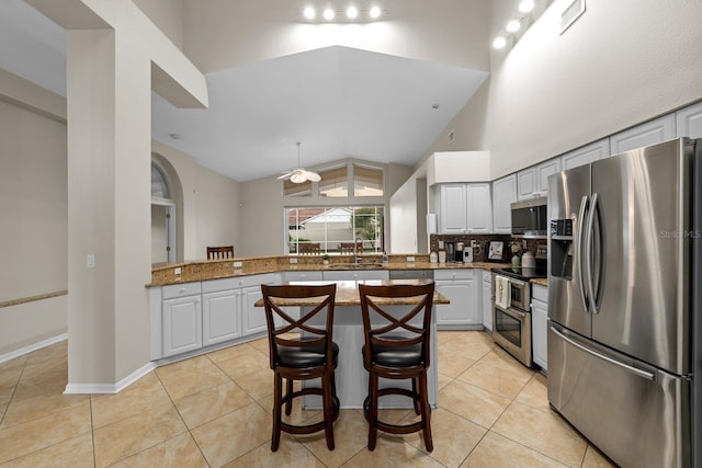 2015 Golf Manor Blvd, Valrico, FL 33596 - kitchen with light tile patterned floors, a peninsula, stainless steel appliances, high vaulted ceiling, and a sink