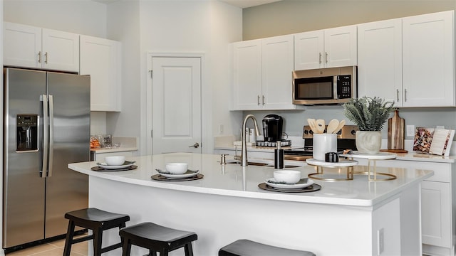 kitchen featuring a breakfast bar area, stainless steel appliances, and white cabinets