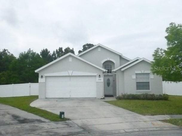 ranch-style home featuring driveway, an attached garage, fence, and a front lawn