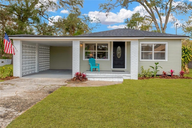 view of front facade with aphalt driveway, brick siding, covered porch, a front yard, and a carport