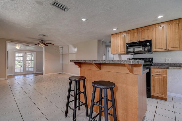 kitchen featuring visible vents, dark countertops, a breakfast bar area, open floor plan, and black appliances