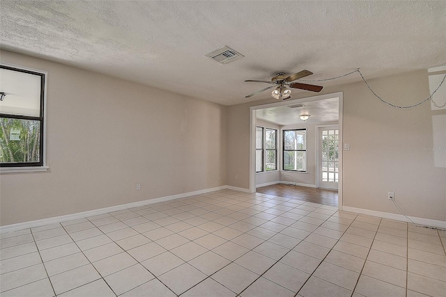 spare room with light tile patterned floors, visible vents, a ceiling fan, a textured ceiling, and baseboards