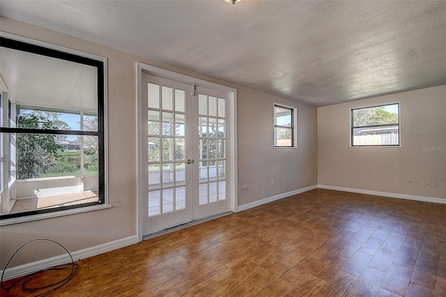 interior space featuring a textured ceiling, baseboards, wood finished floors, and french doors