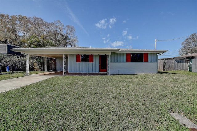 single story home featuring board and batten siding, an attached carport, concrete driveway, and a front lawn