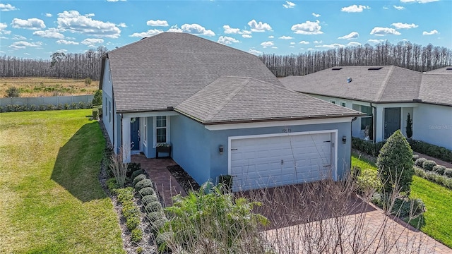 view of front facade featuring aphalt driveway, a garage, roof with shingles, stucco siding, and a front yard