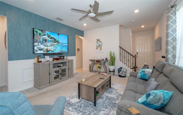 living room with a wainscoted wall, visible vents, light carpet, and wallpapered walls