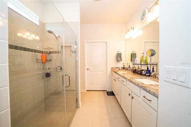 bathroom featuring double vanity, a stall shower, a sink, and tile patterned floors