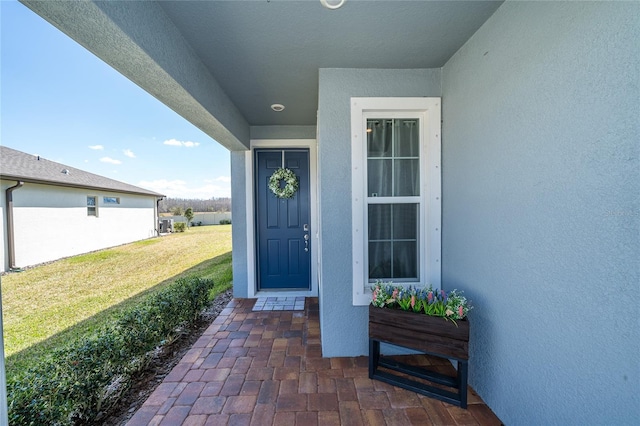 doorway to property with a yard and stucco siding