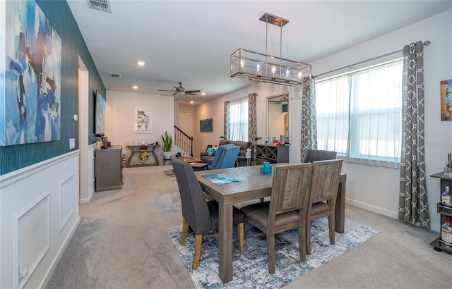 dining room with stairs, visible vents, and light colored carpet