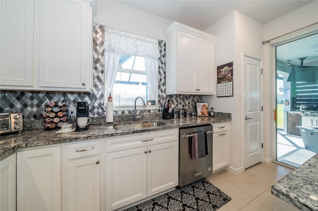 kitchen featuring tasteful backsplash, dishwasher, dark stone countertops, white cabinetry, and a sink