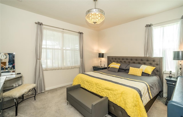 bedroom with light colored carpet, a notable chandelier, and baseboards