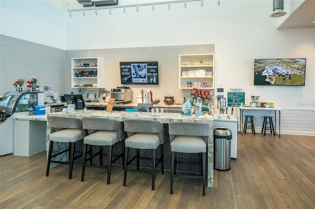 bar with a towering ceiling, built in shelves, and dark wood finished floors