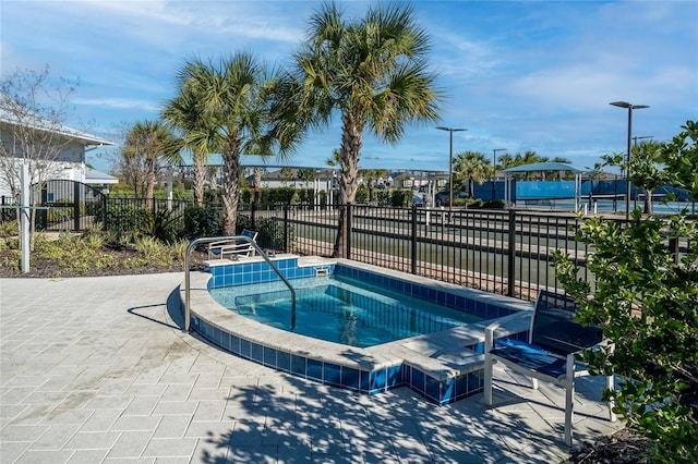 view of swimming pool featuring a community hot tub, fence, and a patio