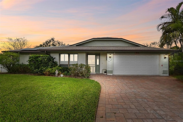 view of front of property with a garage, a front yard, decorative driveway, and stucco siding