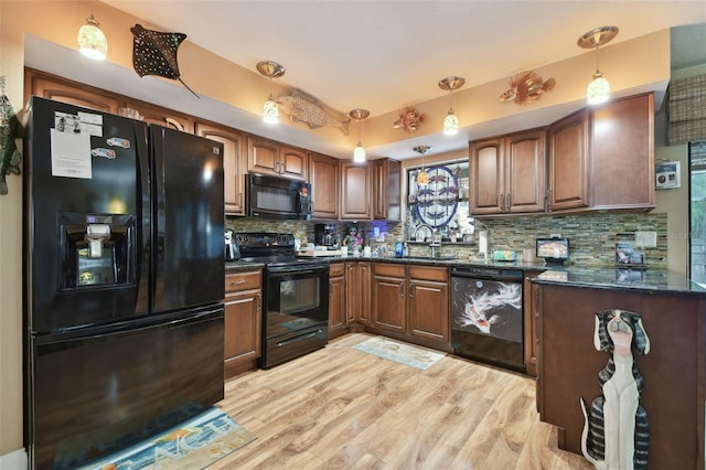 kitchen featuring tasteful backsplash, light wood-style flooring, hanging light fixtures, black appliances, and a sink