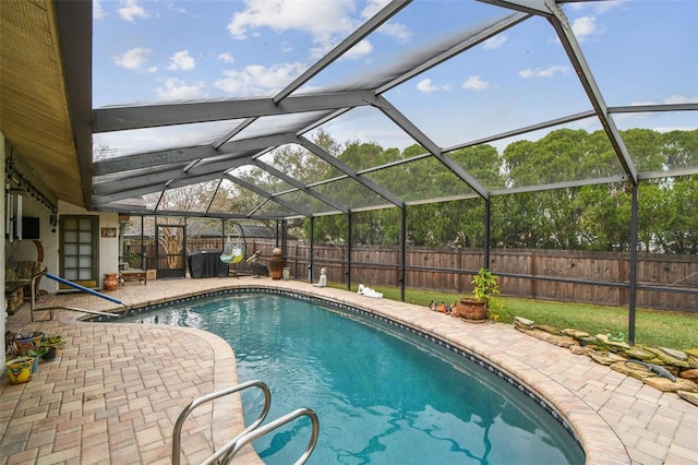 view of swimming pool with glass enclosure, a fenced backyard, a fenced in pool, and a patio