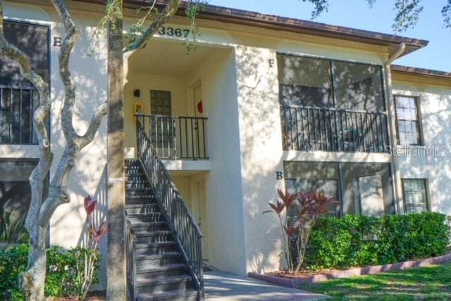 view of side of property with a balcony, stairway, and stucco siding