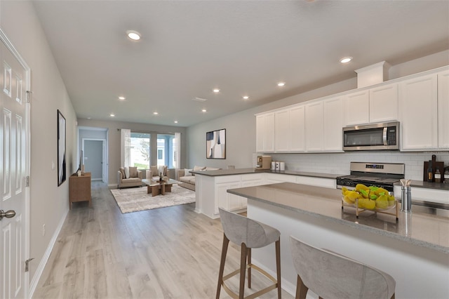 kitchen featuring white cabinets, light stone countertops, appliances with stainless steel finishes, and open floor plan