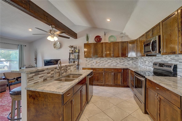 kitchen with a kitchen breakfast bar, stainless steel appliances, vaulted ceiling, light tile patterned floors, and sink