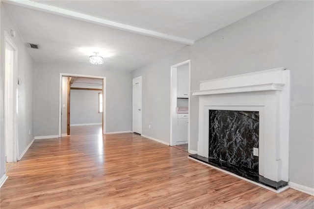 unfurnished living room with beam ceiling and light hardwood / wood-style flooring