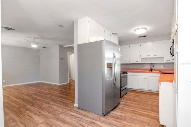 kitchen featuring sink, appliances with stainless steel finishes, white cabinets, and light hardwood / wood-style floors