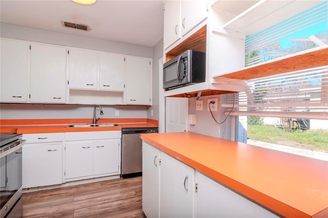 kitchen featuring white cabinets, appliances with stainless steel finishes, sink, and light hardwood / wood-style flooring