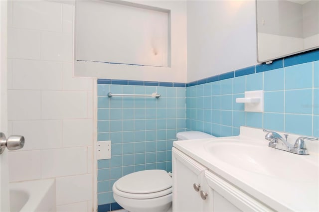 bathroom featuring toilet, tile walls, vanity, and a bathing tub