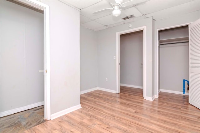 unfurnished bedroom with ceiling fan, light wood-type flooring, a paneled ceiling, and a closet