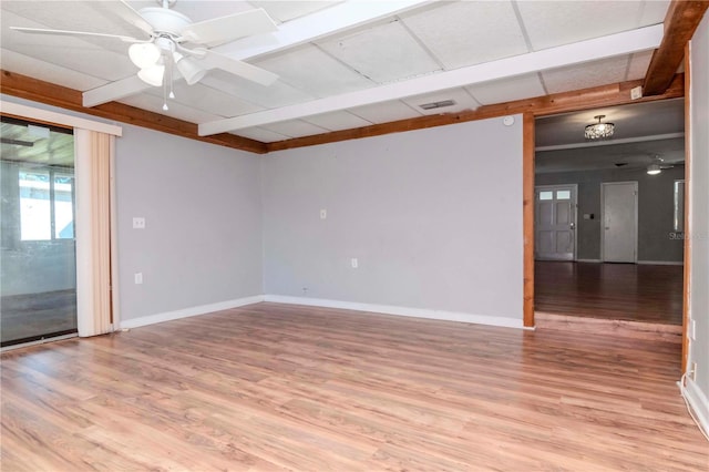 unfurnished room featuring ceiling fan, light wood-type flooring, and beamed ceiling