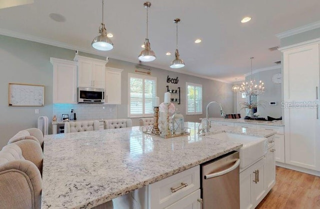 kitchen with sink, stainless steel appliances, a large island with sink, and white cabinets