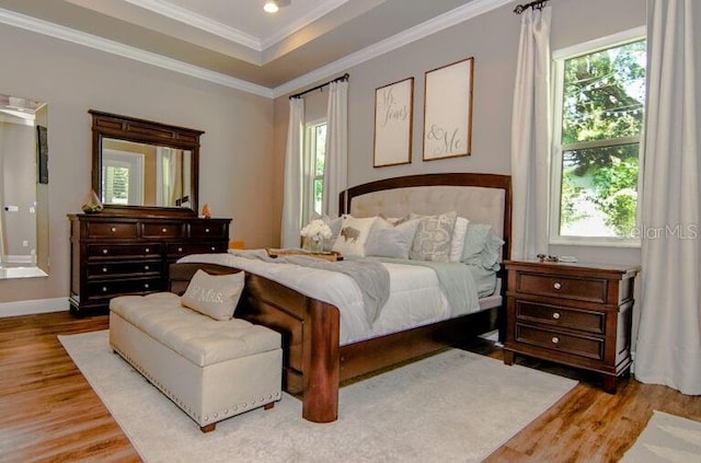 bedroom featuring a tray ceiling, ornamental molding, and light hardwood / wood-style floors