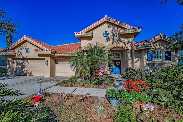 mediterranean / spanish-style house with concrete driveway, a tiled roof, a garage, and stucco siding