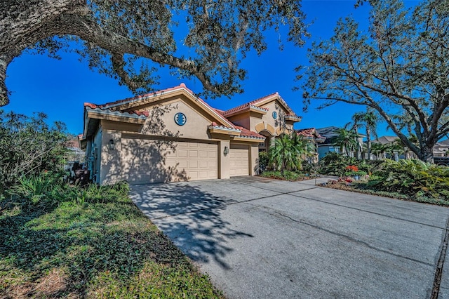 view of front of house featuring a tiled roof, a garage, driveway, and stucco siding