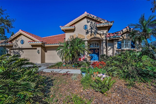 mediterranean / spanish-style house featuring a tile roof, an attached garage, driveway, and stucco siding