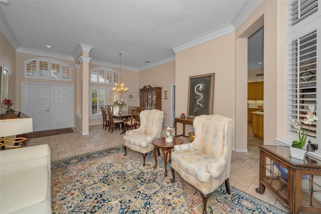 living area featuring decorative columns, baseboards, an inviting chandelier, and crown molding