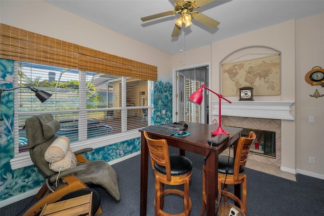 carpeted dining space with a tile fireplace, baseboards, and ceiling fan