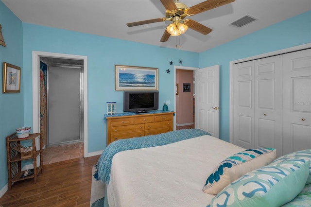 bedroom with dark wood finished floors, visible vents, baseboards, and a closet