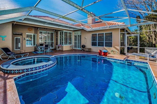 view of pool featuring glass enclosure, a pool with connected hot tub, and a patio area