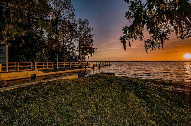 dock area featuring a water view and a lawn