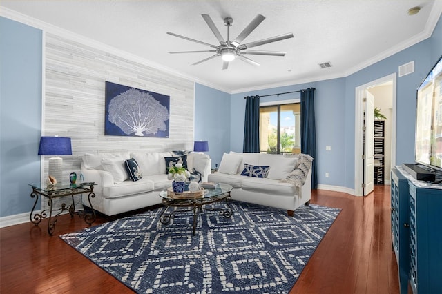 living room featuring dark wood-style floors, an accent wall, baseboards, and crown molding