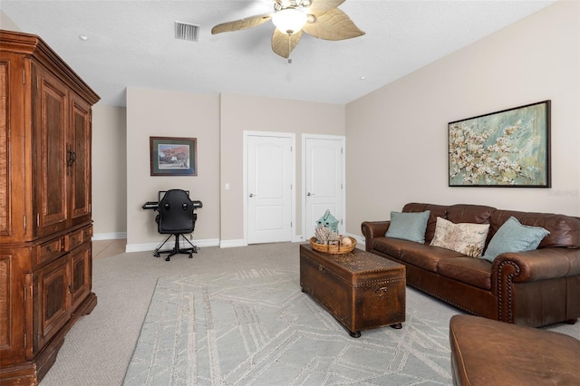 living area featuring ceiling fan, visible vents, baseboards, and light colored carpet