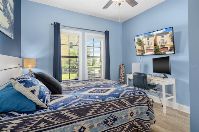 bedroom with light wood-type flooring, a ceiling fan, and baseboards