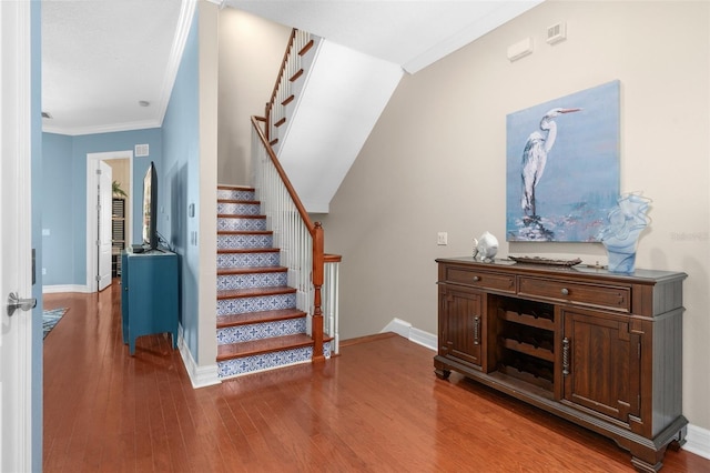 staircase with crown molding, baseboards, and wood finished floors