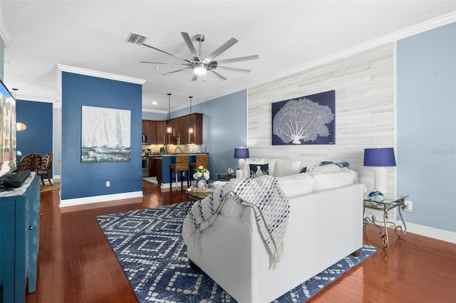 living area featuring dark wood-style floors, an accent wall, visible vents, and ornamental molding