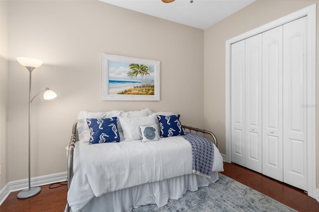 bedroom with a closet, dark wood-style flooring, and baseboards