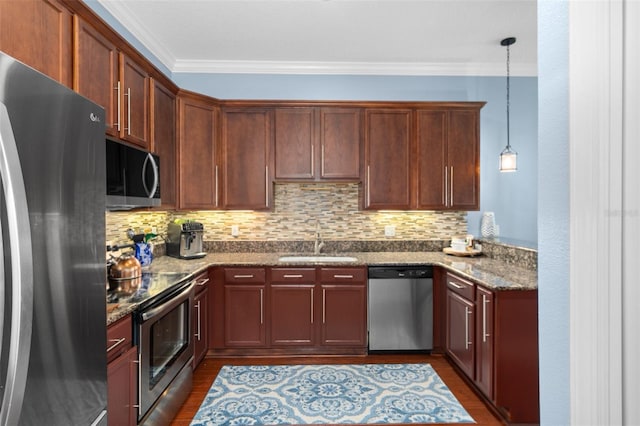 kitchen with stone counters, pendant lighting, crown molding, stainless steel appliances, and a sink