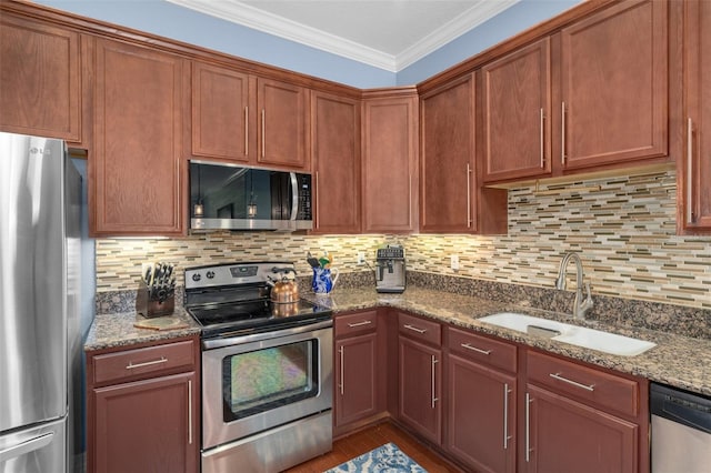 kitchen featuring backsplash, appliances with stainless steel finishes, ornamental molding, a sink, and light stone countertops